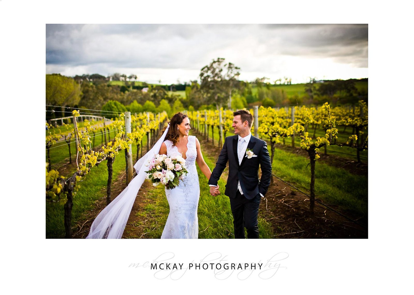 Kayleigh and Josh walk through vine rows at Centennial Vineyards wedding Bowrala